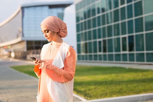 Portrait of Muslim woman wearing Hijab outdoor using mobile phone.