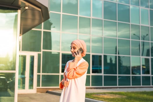 Portrait of Muslim woman wearing Hijab outdoor using mobile phone.