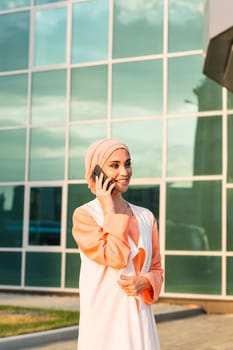 Portrait of Muslim woman wearing Hijab outdoor using mobile phone.