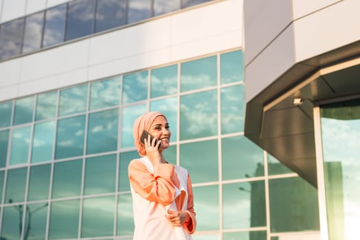 Portrait of Muslim woman wearing Hijab outdoor using mobile phone.