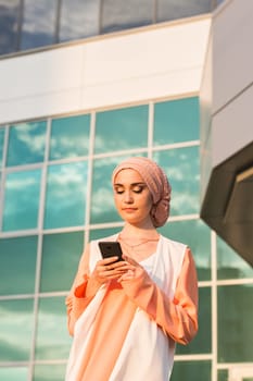 Portrait of Muslim woman wearing Hijab outdoor using mobile phone.