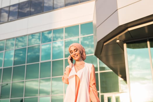 Portrait of Muslim woman wearing Hijab outdoor using mobile phone.