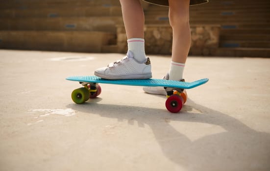 Skateboarding legs. Close-up child legs on a skateboard, skateboarding on a playground outdoors. People. Lifestyle. Leisure activity. Kids entertainment concept. Extreme sport. Childhood