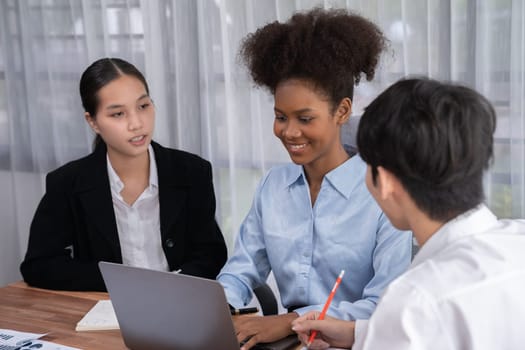 Happy diverse business people work together, discussing in corporate office. Professional and diversity teamwork discuss business plan on desk with laptop. Modern multicultural office worker. Concord