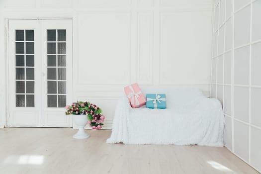 sofa in the interior of the white room with blue and pink gifts for the holiday
