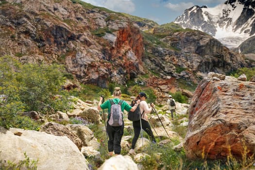 Women with backpacks and scandinavian sticks climb the mountains in Caucasus