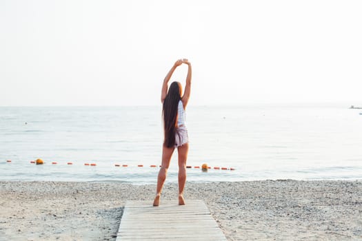 Beautiful woman with long hair walks on the beach yoga
