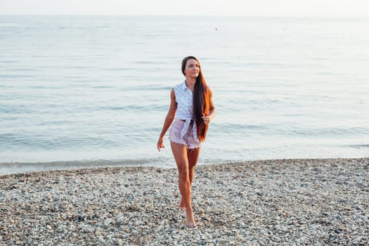 Beautiful woman with long hair walks on the beach yoga