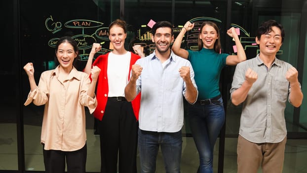 Group of businesspeople applause to celebrate successful project while looking at camera. Professional diverse business team standing at glass wall with marketing strategy, idea,plan. Tracery