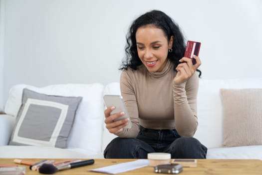 Young happy woman buy product by online shopping at home while ordering items from the internet with credit card online payment system protected by crucial cyber security from online store platform