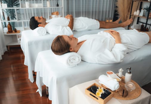 Caucasian couple customer enjoying relaxing anti-stress spa massage and pampering with beauty skin recreation leisure in day light ambient salon spa at luxury resort or hotel. Quiescent