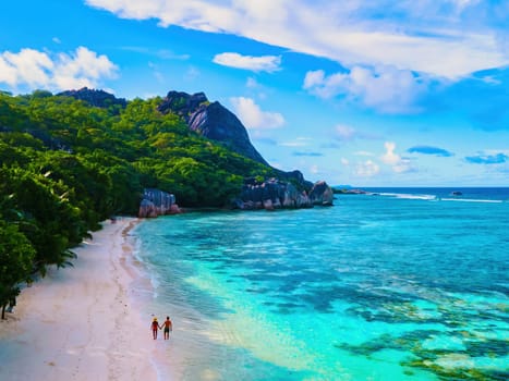 Anse Source d'Argent beach, La Digue Island, Seychelles, couple men and woman walking at the beach during sunset at a luxury vacation at the tropical Islands of Seychelles