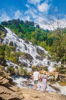 A couple of visits Mae Ya Waterfall Doi Inthanon National Park Thailand Chiang Mai during vacation. Asian women and caucasian men visit a waterfall