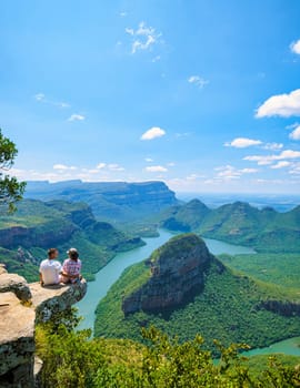 Asian women and Caucasian men on vacation in South Africa visit the Panorama Route of South Africa, the Blyde river canyon with the three rondavels, and the Blyde river canyon in South Africa.