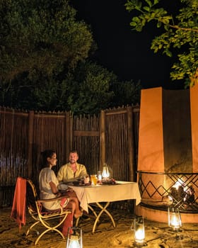 South Africa Kwazulu Natal, a luxury safari lodge in the bush of a Game reserve, a couple of men and an Asian woman having dinner by candlelight