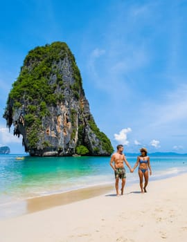 Railay Beach Krabi Thailand, the tropical beach of Railay Krabi, a couple of men in swimshort and women in bikini walking on the beach,