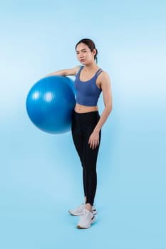 Young attractive asian woman portrait in sportswear with fit ball targeting on abs muscle for effective energetic daily workout routine. Studio shot and isolated background. Vigorous