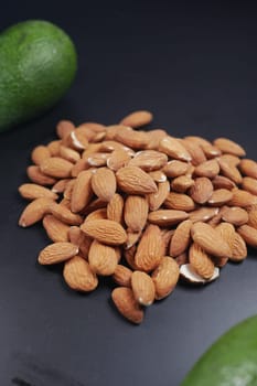 close up of slice of avocado and almond nut on chopping board.,