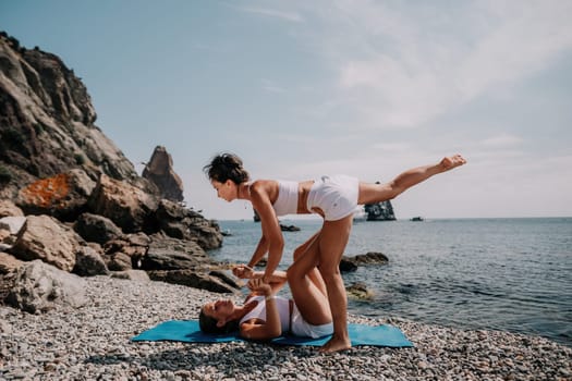 Woman sea yoga. Back view of free calm happy satisfied woman with long hair standing on top rock with yoga position against of sky by the sea. Healthy lifestyle outdoors in nature, fitness concept.