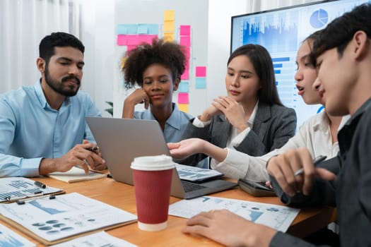 Multiracial analyst team use BI dashboard data to analyze financial report on meeting table. Group of diverse business people utilize data analysis by FIntech for success business marketing. Concord