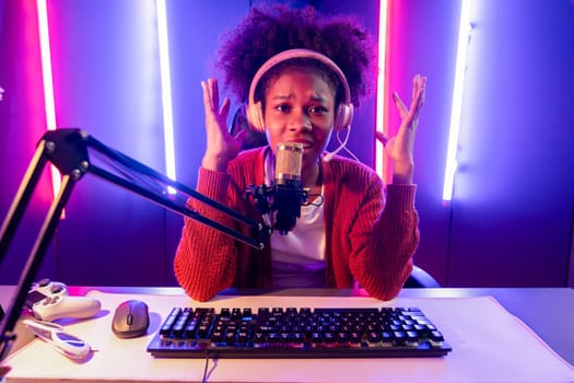 Host channel of gaming streamer, African girl taking, typing with Esport skilled team player and viewers online game in neon color lighting room. Concept of cybersport indoor activities. Tastemaker.