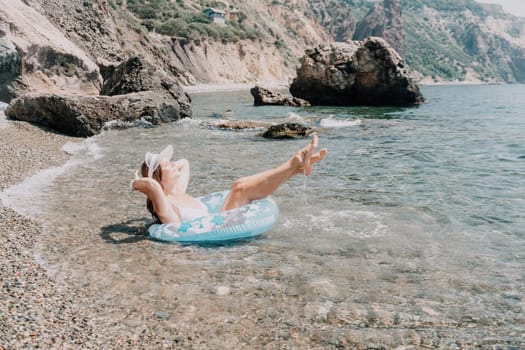 Woman summer sea. Happy woman swimming with inflatable donut on the beach in summer sunny day, surrounded by volcanic mountains. Summer vacation concept