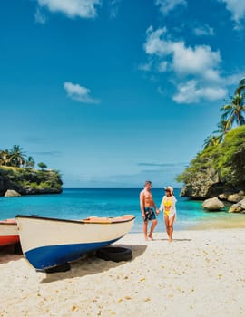 A couple of men and women in swimshorts and bikinis at Playa Lagun Beach Curacao, a couple on a vacation summer holiday in Curacao