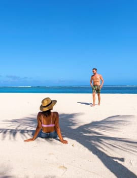 Man and Woman on a tropical beach in Mauritius, a couple on a honeymoon vacation in Mauritius with palm tree shadow on the beach