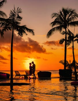 a young couple of men and women at a swimming pool during a vacation on a tropical island. man and woman in an infinity pool during sunset