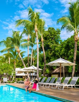 Man and Woman by a swimming pool, a couple on a honeymoon vacation relaxing by the pool