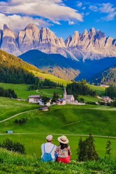 Couple viewing the landscape of Santa Maddalena Village in the Dolomites Italy, Santa Magdalena village Dolomites mountains, Val di Funes