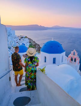 A couple walking at the village of Oia Santorini Greece, men and women visit the whitewashed Greek village of Oia during summer vacation at sunrise over the caldera