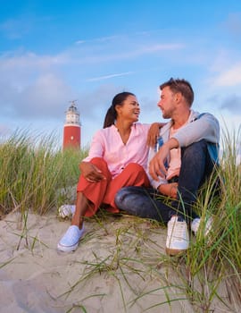 Texel lighthouse during sunset Netherlands Dutch Island Texel Holland, a couple visit the lighthouse, men and woman on vacation Texel watching the sunset by the lighthouse