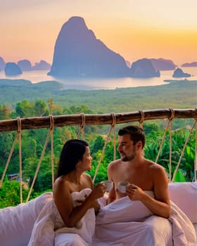 Phangnga Bay Thailand, a couple on vacation watching the sunrise over Phangnga Bay Samethnagshe viewpoint honeymoon from an outdoor bedroom with pillows and coffee during sunrise in bed