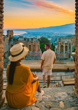 Taormina Sicily, couple watching the sunset at the Ruins of the Ancient Greek Theater in Taormina, Sicily. couple mid age on vacation in Sicilia during the summer holidays