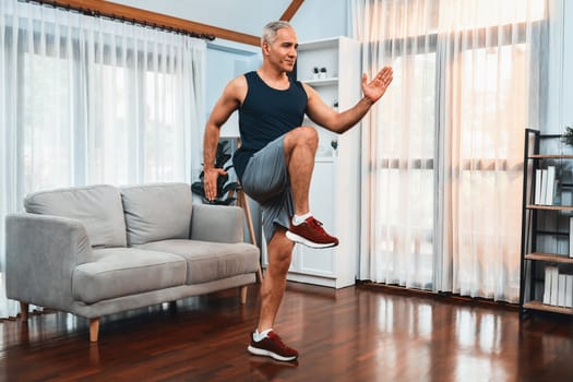 Athletic and sporty senior man make running pose at home. Healthy fit body lifestyle as home workout exercise concept after retirement. Clout