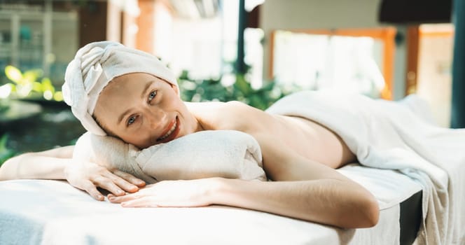 Beautiful young woman relaxes on a spa bed surrounded by nature. ready for a body massage. Attractive female in white towel lying peacefully during waiting for body massage. Close up. Tranquility