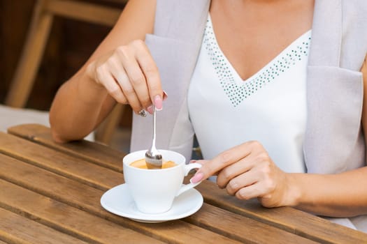 Positive business woman sitting in outdoor cafe drinking coffee