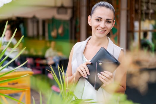 Beautiful woman smiling happy standing at city. Notepad in hand standing