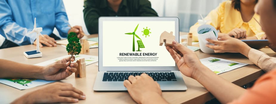 Renewable energy logo displayed on green business laptop while business team represented green design to customer. ESG environment social governance and Eco conservative concept. Closeup. Delineation.