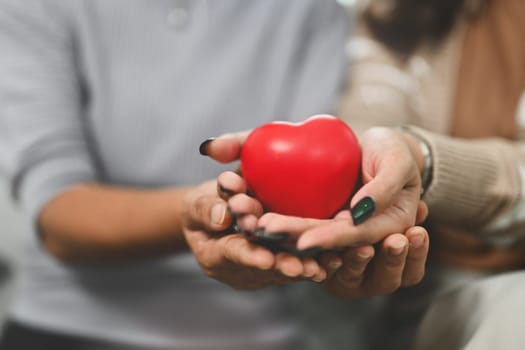 Senior woman and young woman hands holding red heart. Health care, insurance and world heart day concept.