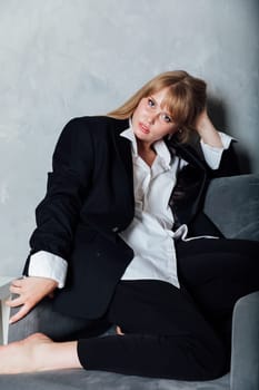 Beautiful fashionable woman in black business suit sitting on a chair