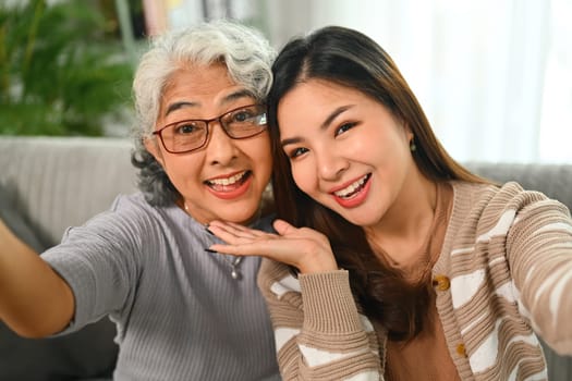 Head shot happy mature mother grownup daughter taking selfie on smartphone together.