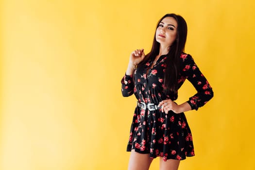 brunette woman in dress with flowers on yellow background