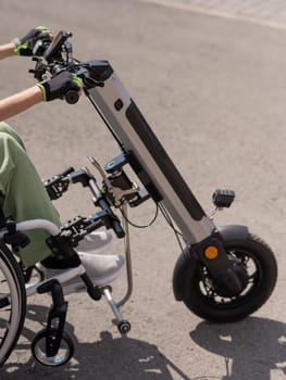 A woman controls a wheelchair using a special manual device. Close up an electric handbike