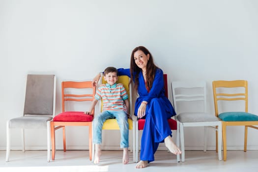 Boy and woman and many different chairs in the interior of a white room