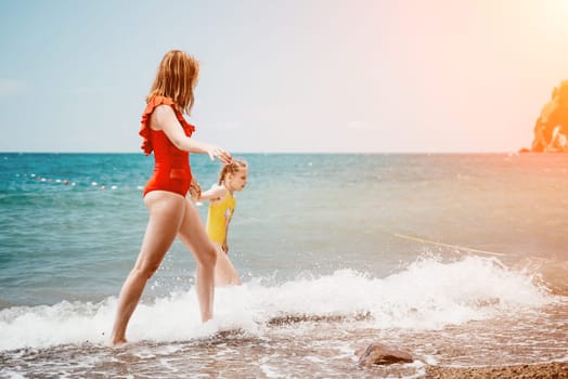 Happy loving family mother and daughter having fun together on the beach. Mum playing with her kid in holiday vacation next to the ocean - Family lifestyle and love concept.