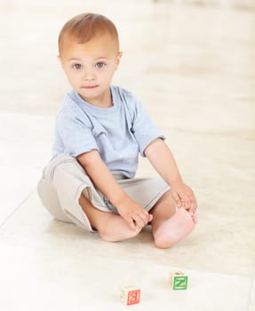 Cute, building blocks and portrait of infant at his home playing for child development and growth. Sweet, youth and boy newborn, baby or kid having fun and standing with toys in a modern house