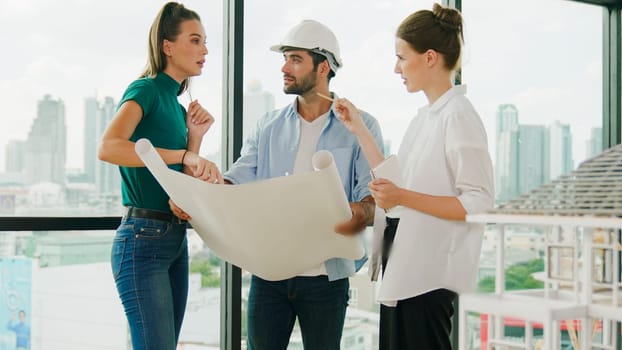 Professional architect engineer team talking, sharing, brainstorming about design while manager hold at project plan. Young architect holding plan while manager listen and point at plan. Tracery