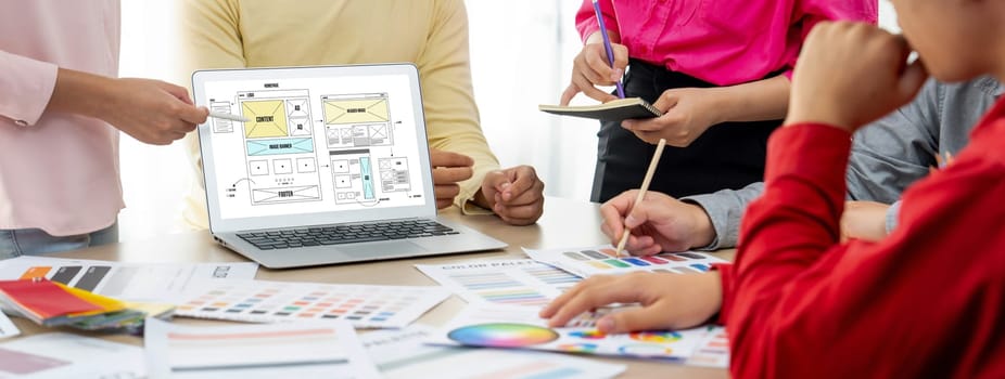 Cropped image of interior designer team discuss the material color while laptop displayed website wireframe designs for mobiles app and website. Creative design and business concept. Variegated.